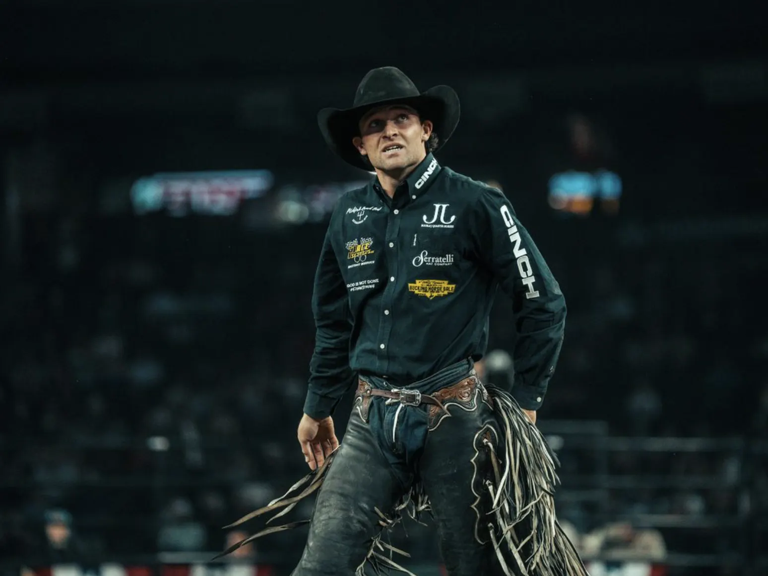 Rodeo athlete in a cowboy hat walking the arena with his rope