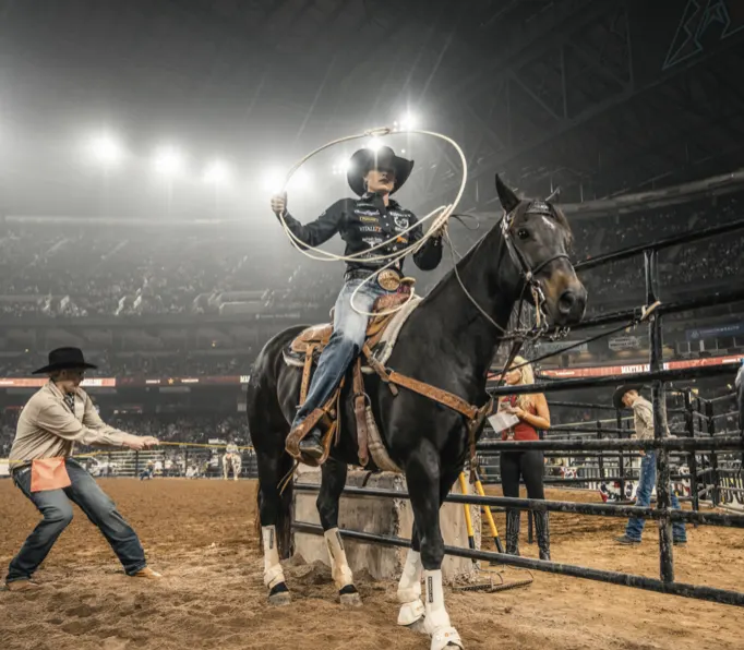 Cowboy on horseback raising his rope in the arena
