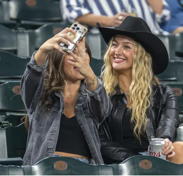 Two fans in cowboy hats taking a selfie in the stands