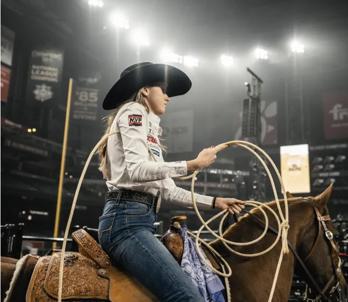 Breakaway roper on horseback with her rope in the arena