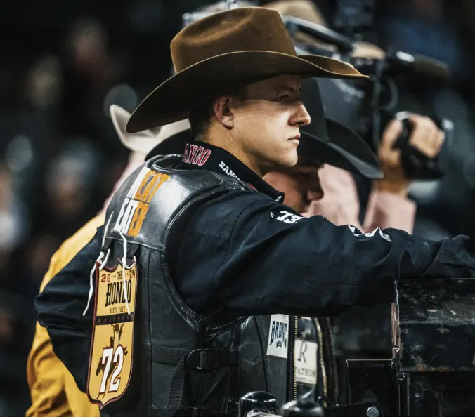 Rodeo athlete in a cowboy hat behind the chutes