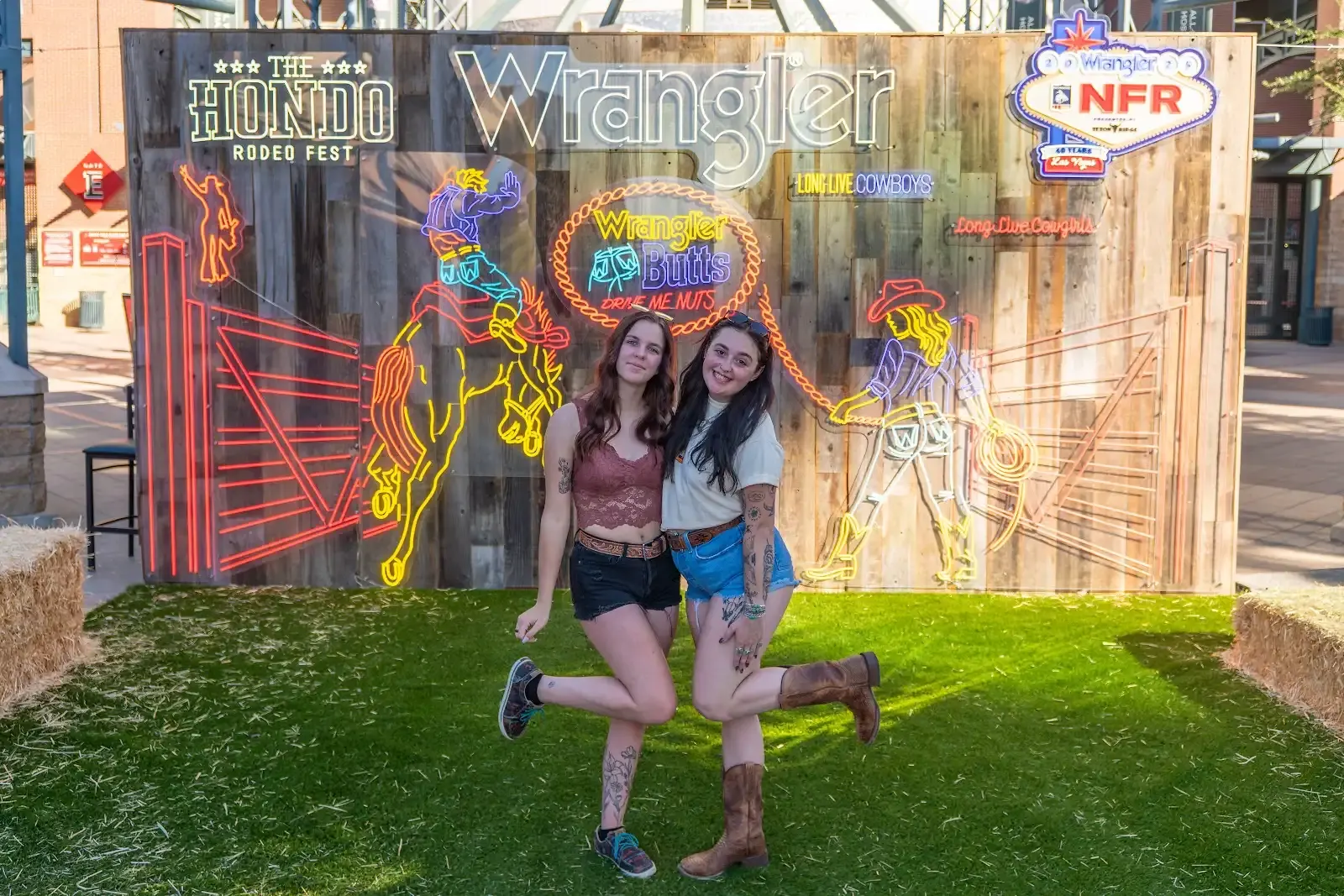 Two fans posing at a photo wall at the Hondo Street Fest