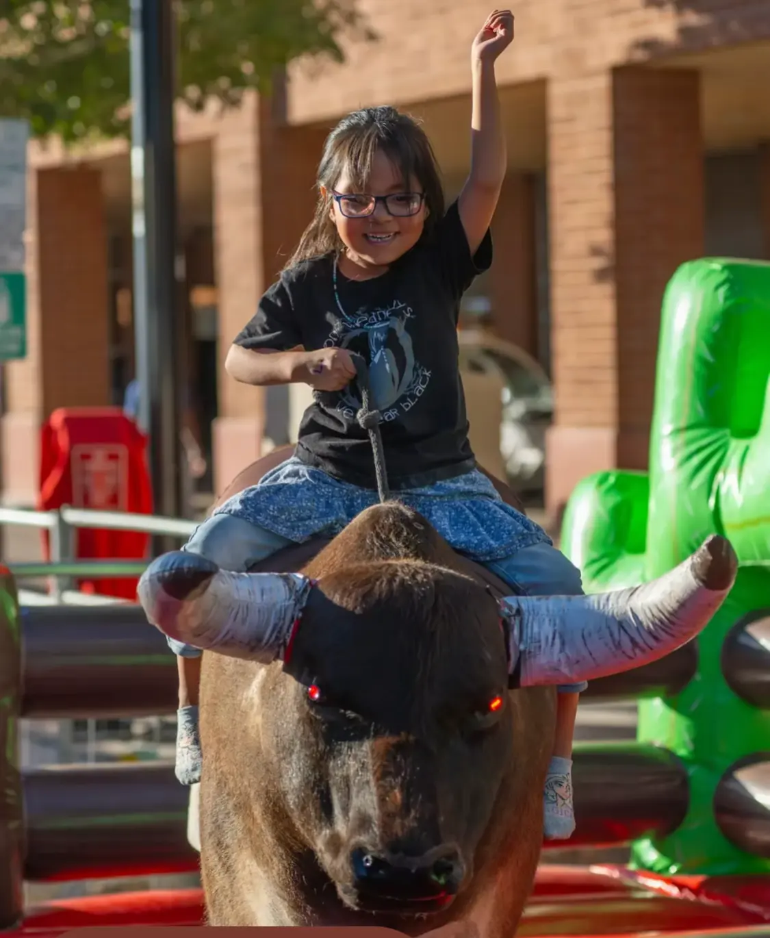 A girl riding a mechanical bull at the street fest