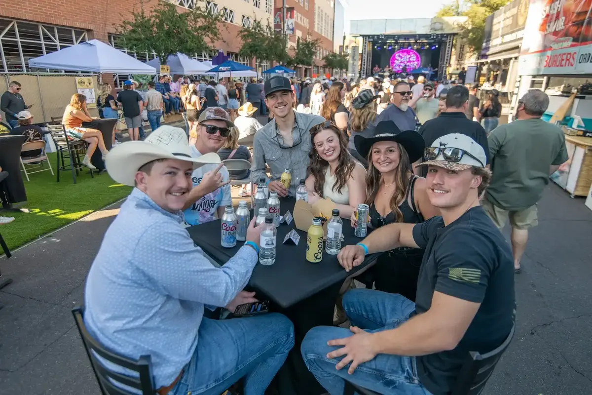 Friends at a table with a live music stage behind them